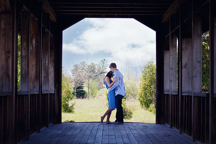 man in blue long-sleeved shirt embracing woman in blue dress