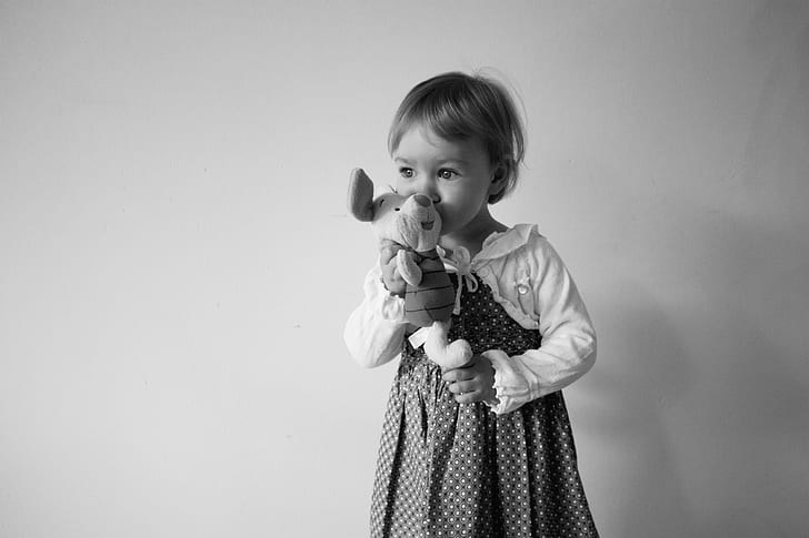 grayscale photo of girl holding Winnie The Pooh Piglet plush toy