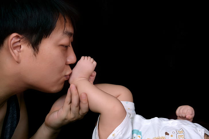 man kissing baby's foot