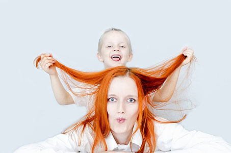 closeup photo of a woman with a boy in her back holding her hair