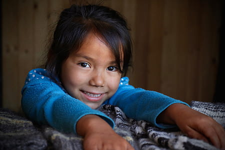 girl wearing blue sweater leaning on white and black textile while smiling