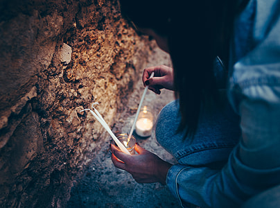 woman lighting candles near rocks