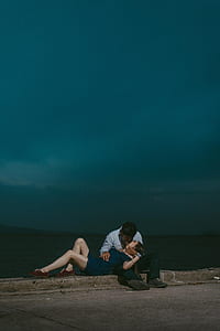 man kissing the woman lying on his legs