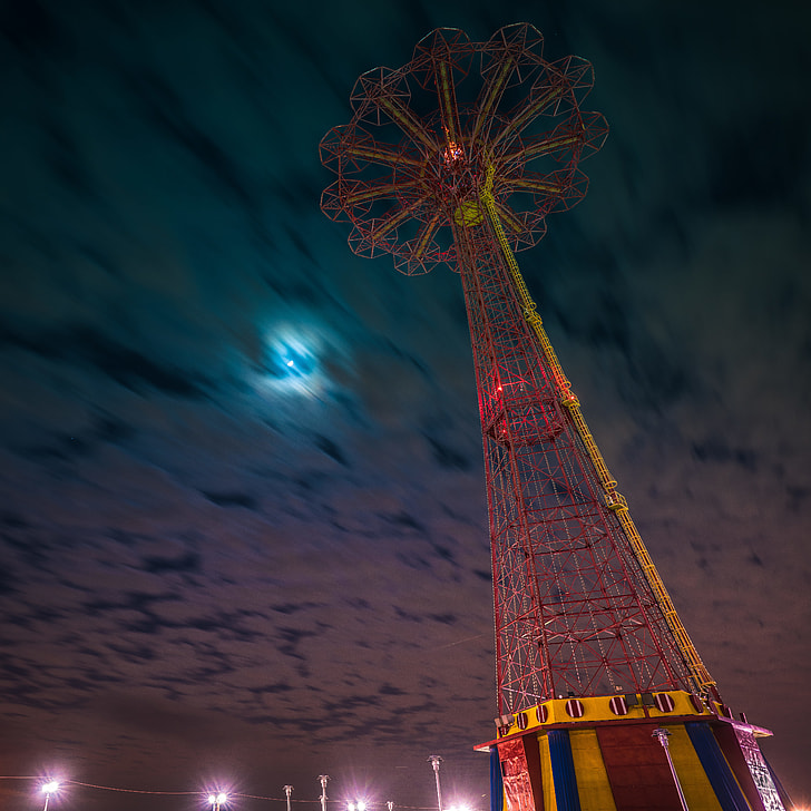 red and yellow amusement park ride under cloudy night sky