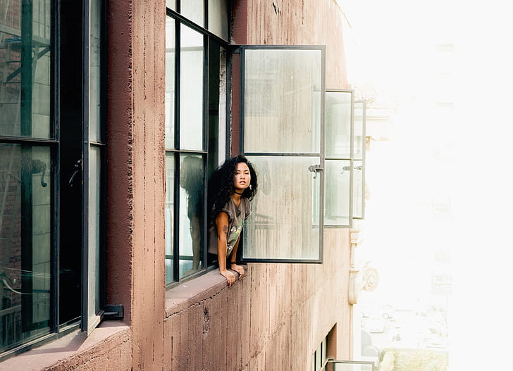 woman leaning on window during daytime