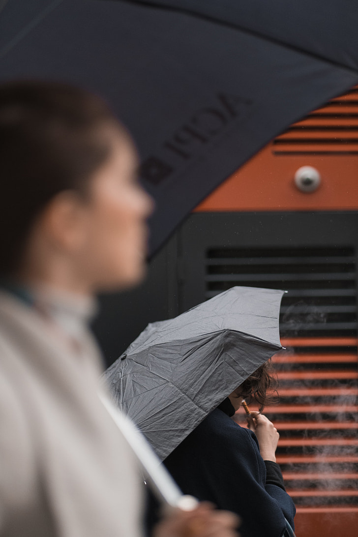 two person using black umbrellas