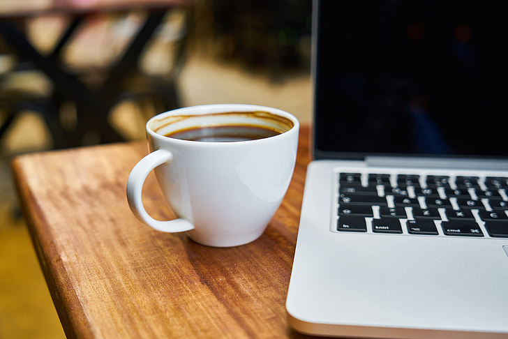 coffee mug beside MacBook