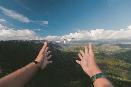 quadcopter drone in front of person and mountains in background