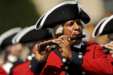 Man in Red and White Musical Suit Playing Flute during Daytime in Camera Focus Photography