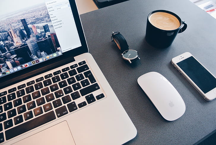 MacBook pro near Apple Magic Keyboard, silver iPhone 5s, and black ceramic mug