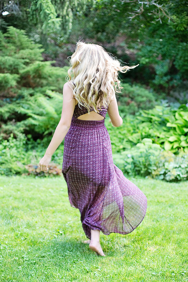 woman in purple sleeveless dress running on green grass