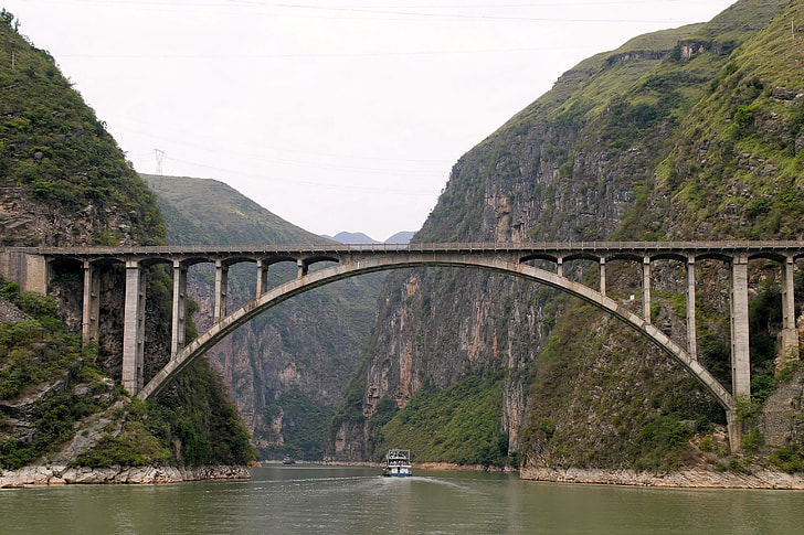 gray concrete bridge near over river near mountains