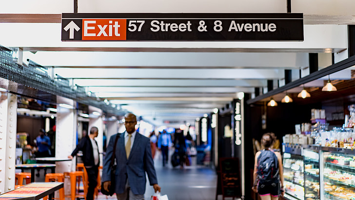 Exit 57 Street & 8 Avenue signage above people walking nearby