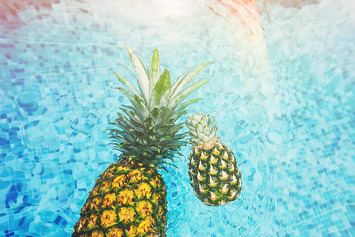 two pineapples on body of water during daytime