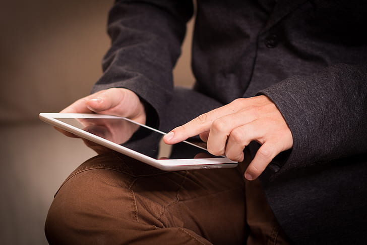 person wearing black dress shirt and brown pants holding white ipad