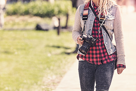 selective focus photo of woman holding DSLR camera