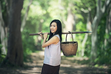 woman holding stick with basket on her back