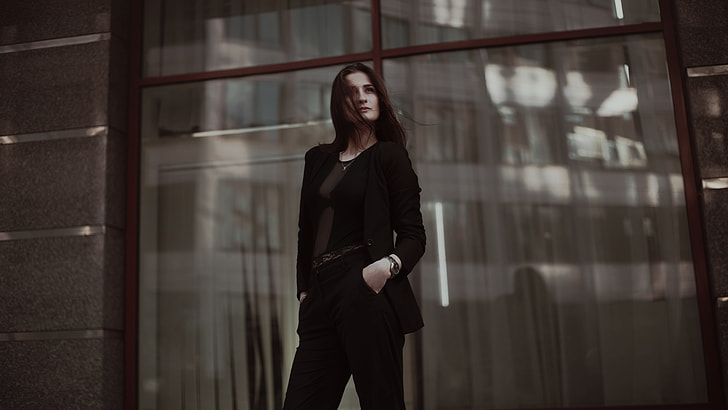 woman in black blazer and black pants standing near glass window