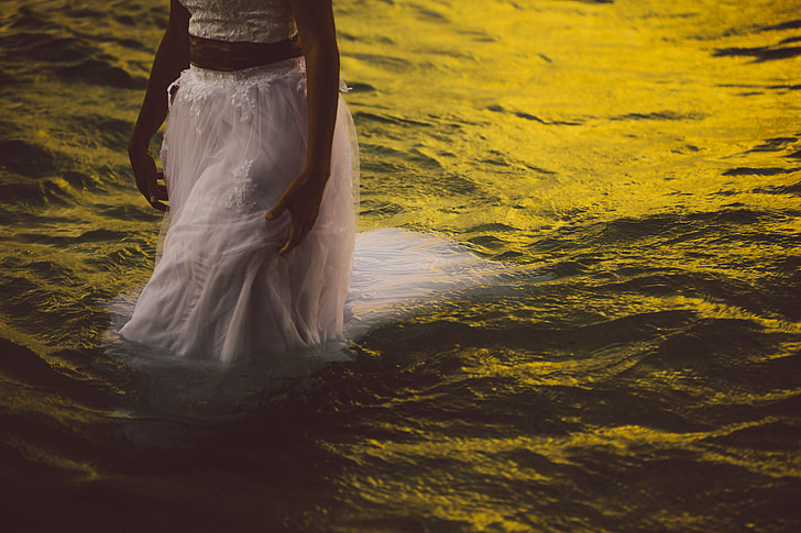 woman wearing white walking on body of water