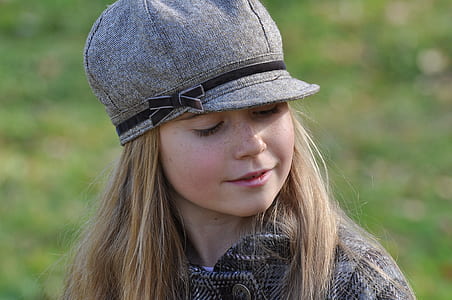 close-up photography of girl wearing grey coat and grey cap during daytime