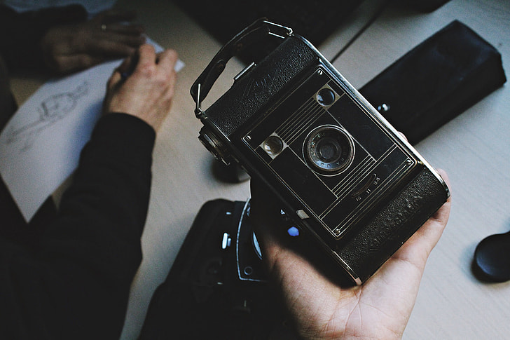 person holding black vintage camera