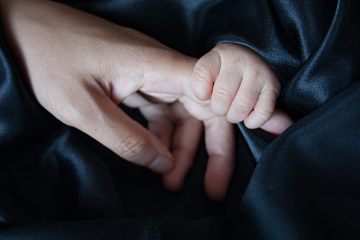 baby holding person's finger