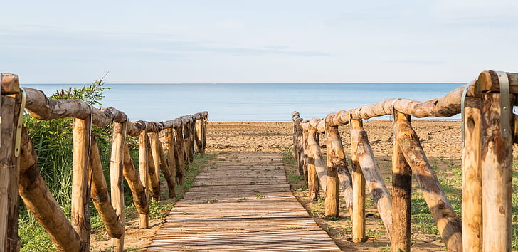 empty wooden pathway leading towards ocean