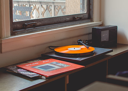black and orange vinyl player beside clear glass window