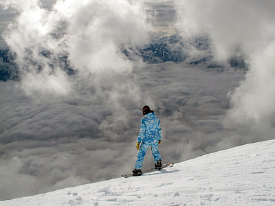 person wearing blue ski uit with board on top of snowy mountain