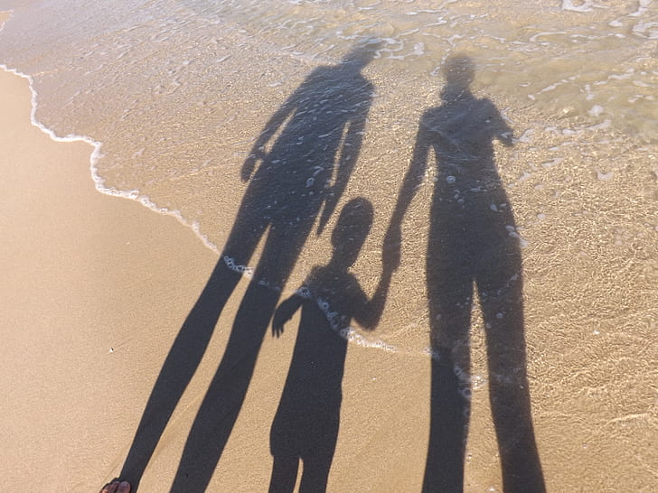 shadow of three person on brown sand
