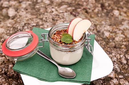 cereal with milk and apple slice in clear glass canister