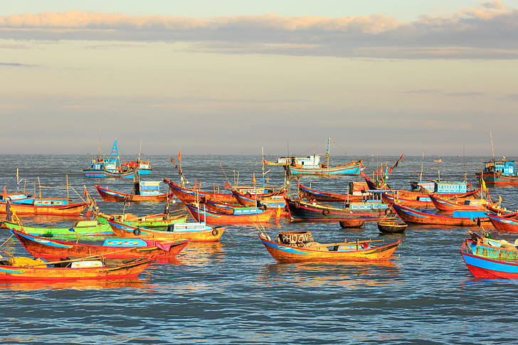 orange boats on body of water during golden hour