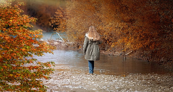 woman wearing gray jacket near body of water