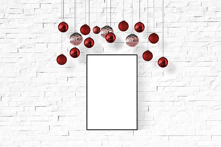 red Christmas baubles hanging behind white painted surface