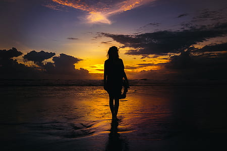 woman walking on sea during sunset