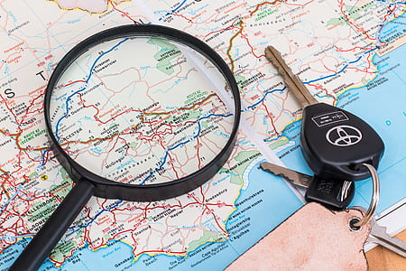 black magnifying glass beside black Toyota key on map