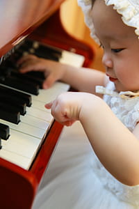 baby wearing white mesh sleeveless dress playing piano photography