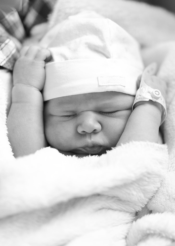 grayscale photo of newborn baby closing her eyes