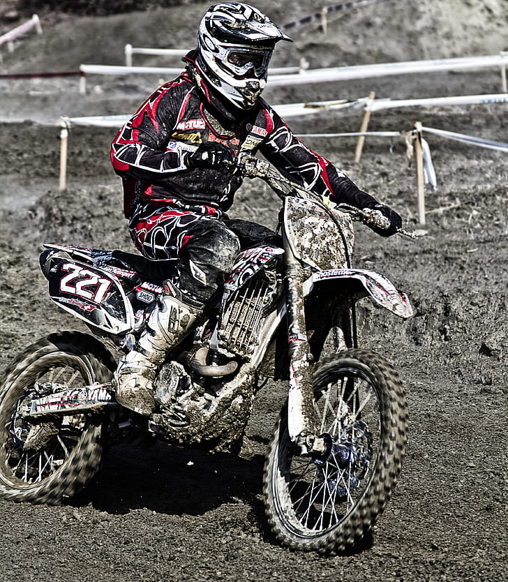 man with red and black racing suit riding on black and white dirt bike motocross during daytime