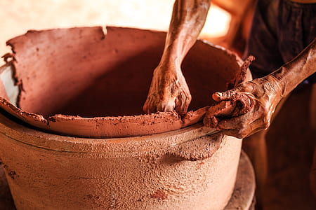 person holding brown clay pot