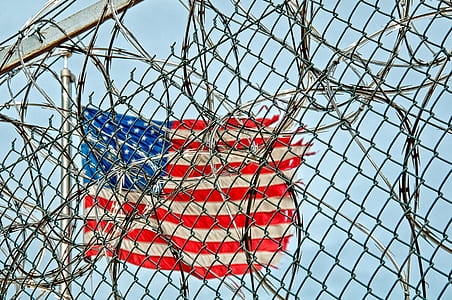 American flag beside gray wire link fence with live wire fence at daytime