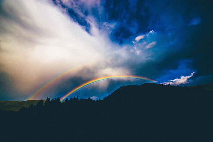 silhouette photography of mountain with rainbows