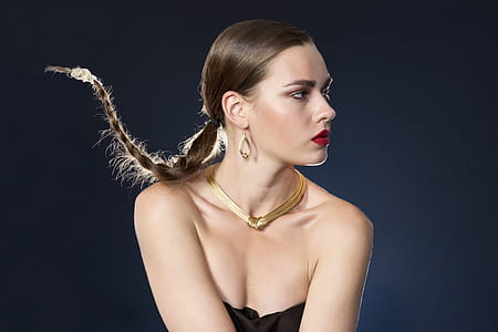 woman wearing gold-colored herringbone necklace and black tube tops with red lipstick and braided hair