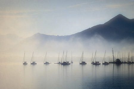brown boats on lake with fogs near mountain