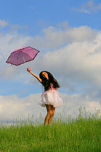 woman with pink and white dress holding pink umbrella on grass field