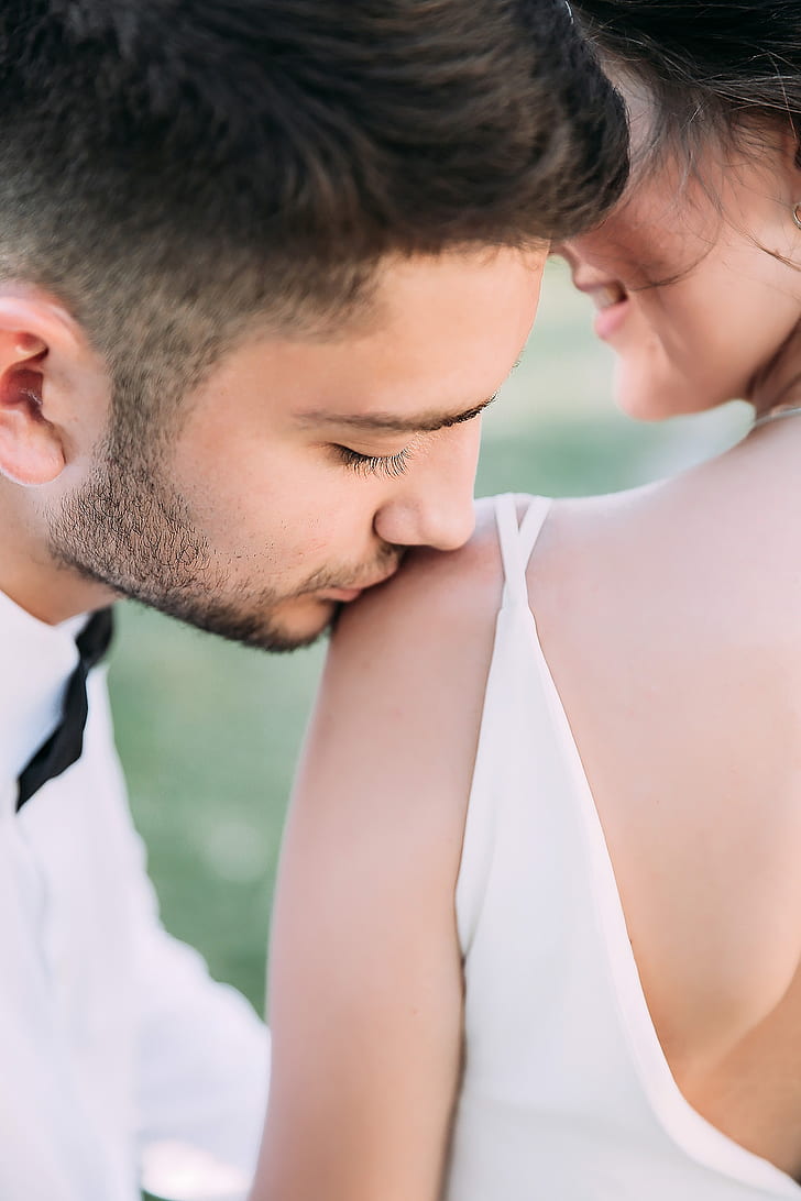 man kissing woman on left shoulder