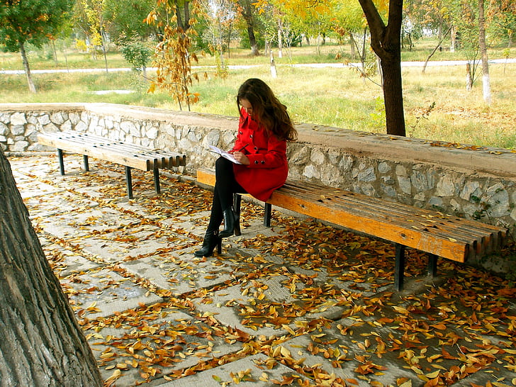 woman in red coat sitting on a bench