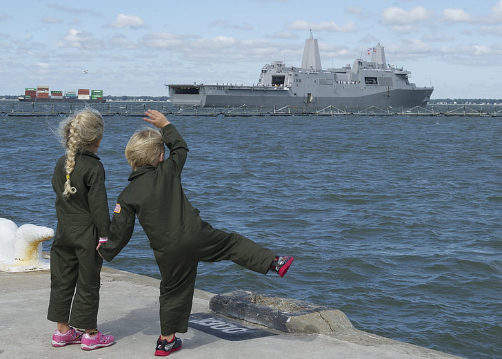two children waving at the ship