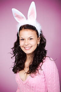 smiling woman with bunny headband and pink v-neck knit sweater\