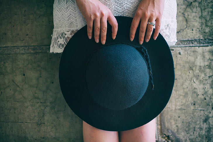 woman holding black sun hat